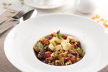 muesli on a white plate on white wooden background