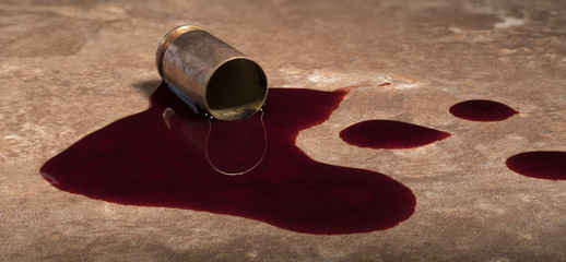 Empty handgun round and blood on a beige floor tile