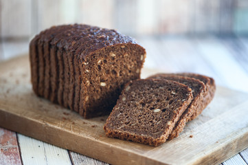 Whole-wheat bread with seeds cut on a wooden board on a natural background. Healthy food, healthy food.