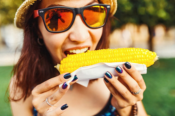 woman eating a delicious tasty corn in city park