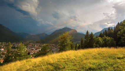 Sun beams, yellow grassy hill and mountains around city of Mittenwald, Germany