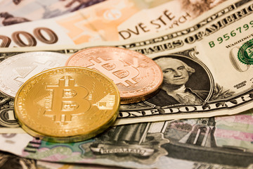 Symbolic coins of bitcoin on banknotes of US dollars, czech crowns and Russian rubles.
