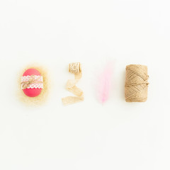 Stylish Easter composition with pink eggs with twine, feather and tapes on white background, Top view, Fat lay. Easter holiday