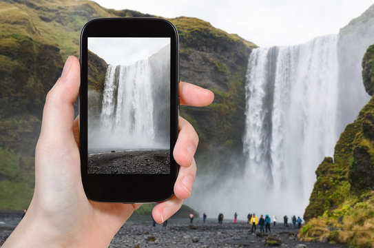 tourist photographs Skogafoss waterfall in Iceland