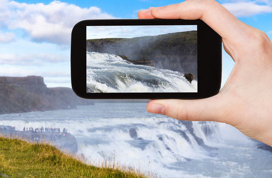 tourist photographs water of Gullfoss waterfall