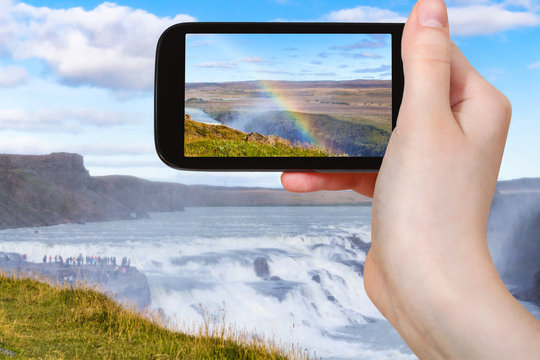 tourist photographs rainbow at Gullfoss waterfall
