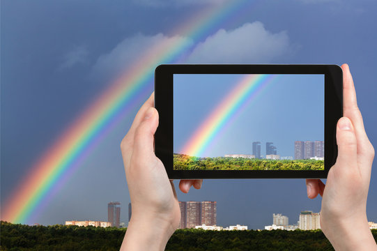 tourist photographs rainbow in dark blue sky