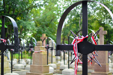 Ribbon with national colours of Poland tied up to the old cross on the cemetery. Warsaw uprising concept.