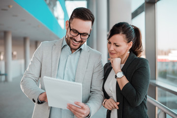Cheerful business people discussing documents in office hall.