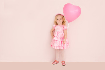 Happy cute little girl  with pink balloon heart on a pink background. mother's day, birthday