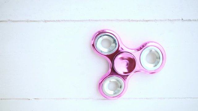 Pink fidget spinner turning on wood background with copy space