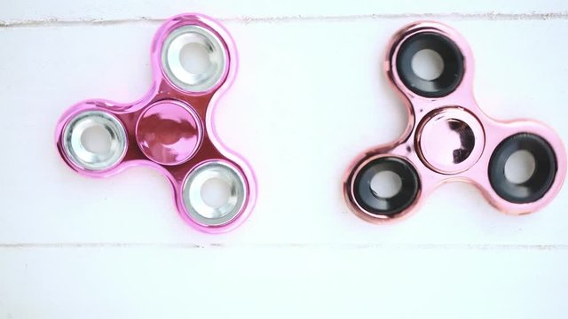 Two pink fidget spinners, one slows down much earlier than the other one.