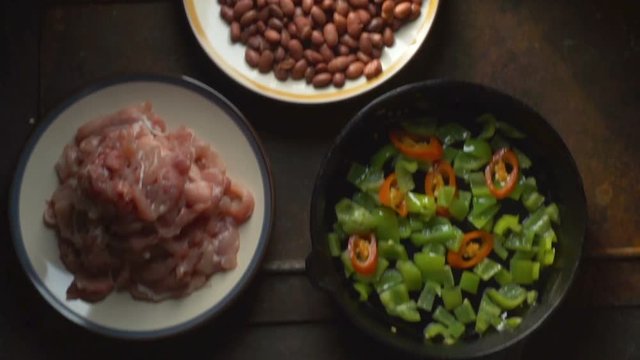 Pieces of chicken, beans. Pepper and chili in a frying pan view from above. Video