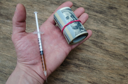 hand with a syringe and money