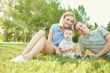 Portrait of a happy family in the park. Mother father and child in the park together.