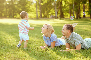 Fototapeta premium Happy family in nature. Parents with a child play in park.