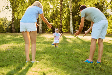 Happy family in nature. Parents with a child play in park.
