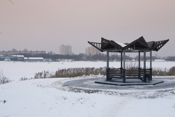 Snow-covered trees and benches in the city park.