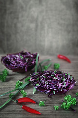 Shredded red cabbage in a bowl of cabbage leaf on a dark background. Vegetarian organic healthy food.