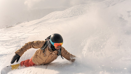Male bearded snowboarder in sportswear and helmet riding down the powder snow hill