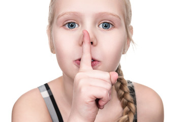 Fototapeta premium Portrait of little girl with finger near mouth, close-up, isolated on white background