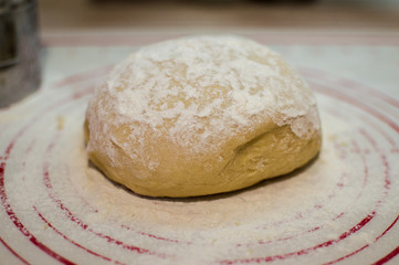 Close-up view of the homemade raw wheat dough ball lying on the modern cooking surface. Dough for pizza, pasta, potstickers.