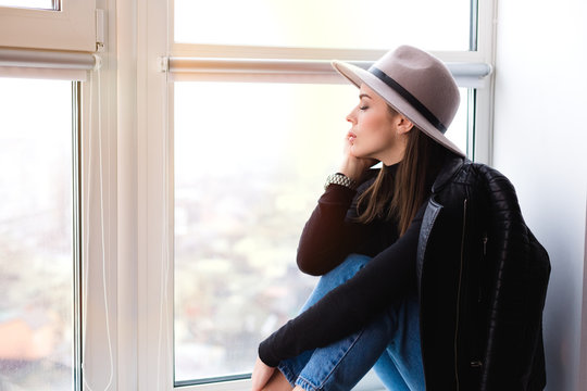 Beautiful boho woman in wool hat sitting by the window