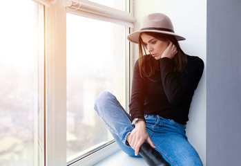 Beautiful boho woman in wool hat sitting by the window