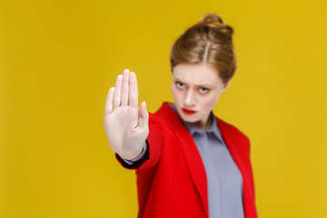 Ban sign. Ginger red head business woman in red suit showing stop hand.