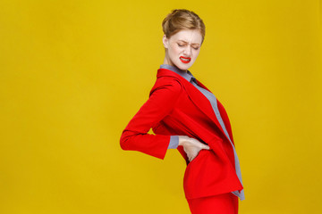 Redhead business woman in red suit have kidneys pain or back.