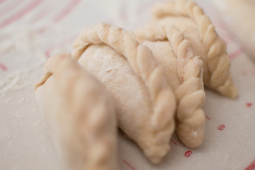 Homemade potstickers with flour laying on the modern cooking surface.