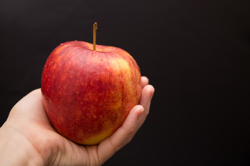 a ripe red and yellow apple in woman's hand