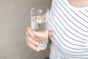 Closeup young woman holding drinking water glass in her hand. Health care concept.