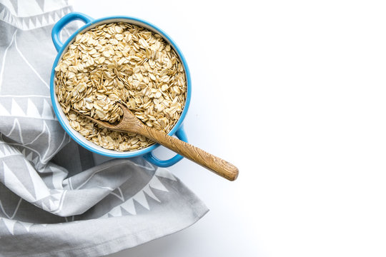 Rolled oats flakes breakfast. Dry oatmeal in bowl isolated on white background. Top view. Delicious Vegan food a hearty cereal
