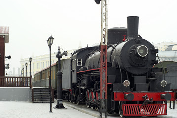 Fototapeta na wymiar vintage steam locomotive with wagons standing at the railway station in winter