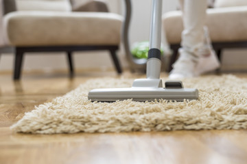 Close up of woman cleaning carpet with vacuum cleaner 