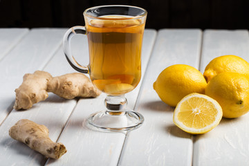 A cup of ginger tea with lemon on a wooden background.