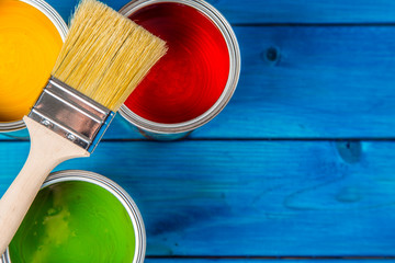 Paint cans color palette, cans opened with brushes on blue table