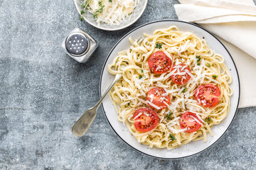 cooked noodles on a table in a plate with tomatoes, parmesan cheese and spices