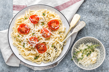 cooked noodles on a table in a plate with tomatoes, parmesan cheese and spices