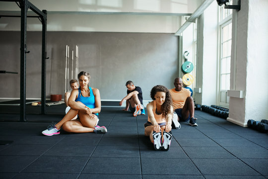 Diverse group of people stretching before a gym workout