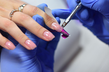Manicurist with a brush applied to the nails a special gel