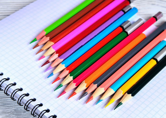 Color pencils lying on a pad with a spiral. Gray natural background, blur