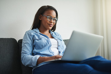 Young African woman relaxing at home using a laptop