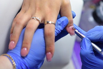 Manicurist with a brush applied to the nails a special gel