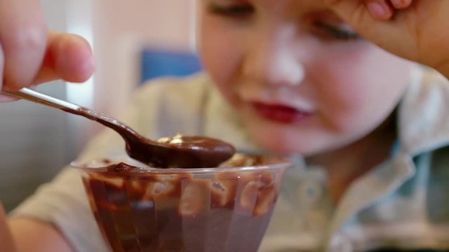 Boy eating his chocolate pudding at the restaurant table