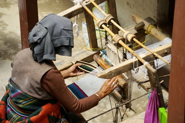  Old Nepalese woman manually braids the mat on an old homemade loom, in the city of Lo Mantang, the capital of the Upper Mustang. Nepal.