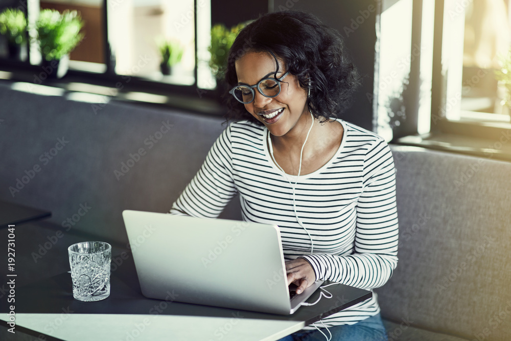 Wall mural Smiling young African woman enjoying a chat online