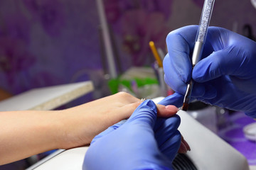 Manicurist with a brush applied to the nails a special gel