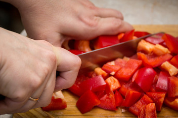 Obraz na płótnie Canvas Close up of hands cutting vegetables with a knife